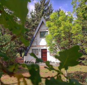 uma pequena casa com uma porta vermelha na floresta em Buenavista Cabañas em Los Reartes