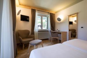 a room with a bed, chair and a window at Hotel Medil in Campitello di Fassa