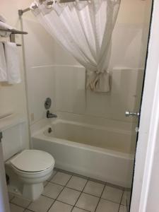 y baño con aseo blanco, bañera y aseo. en Budget Inn Laramie en Laramie