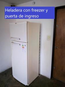 una nevera blanca en una habitación con puerta en Amplio 2 Dormitorios en Cofico en Córdoba