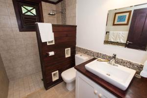 a bathroom with a sink and a toilet and a mirror at Santosha Barbados in Saint Andrew