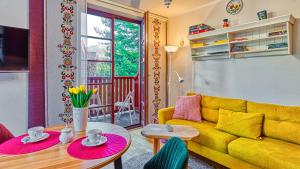 a living room with a yellow couch and a table at Apartament z Sauną pod Świerkami - 5D Apartamenty in Karpacz