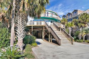 a house with a staircase leading to a building with palm trees at 510 W Ashley-Mountain to Sea in Folly Beach