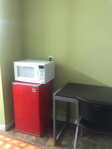 kuchenka mikrofalowa na czerwonej lodówce obok stołu w obiekcie RED CROWN INN w mieście Dallas