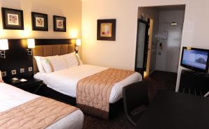 a hotel room with two beds and a flat screen tv at Holiday Inn Telford Ironbridge, an IHG Hotel in Telford