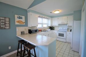 a kitchen with white cabinets and a counter with stools at Salty Shack Unit C - Salty Shack - Dog Friendly Home - Across from the Beach - Central Location! in Folly Beach