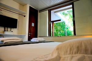 a bedroom with a bed with a mirror and a window at Chalés Maritacas in Maresias