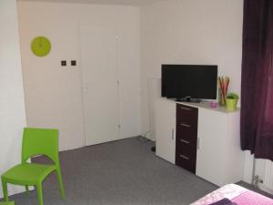 uma sala de estar com uma televisão e uma cadeira verde em Penzion Muraty em Ostrava