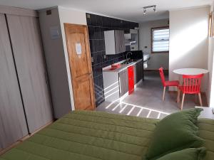 a bedroom with a green bed and a kitchen at Lodging Quirinal in El Tabo