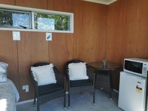 Zimmer mit 2 Stühlen, einem Tisch und einer Mikrowelle in der Unterkunft Waihi Gold Alpacas 1 or 2 people in Waihi
