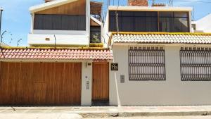a white house with two doors and a fence at Hostal Camiluz in Nazca