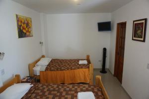 a small room with two beds and a television at Hostal Camiluz in Nazca