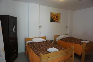 a bedroom with two beds and a picture of oranges on the wall at Hostal Camiluz in Nazca