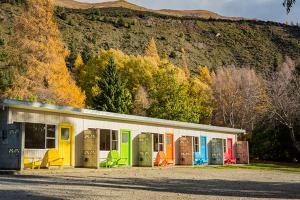 a building with colorful doors and windows next to a mountain at The Camp - Lake Hawea in Lake Hawea