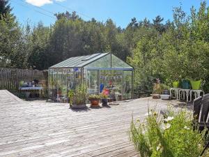 einen Garten mit einem Gewächshaus und Topfpflanzen auf einer Holzterrasse in der Unterkunft 8 person holiday home in FAGERFJ LL R NN NG in Bräcke