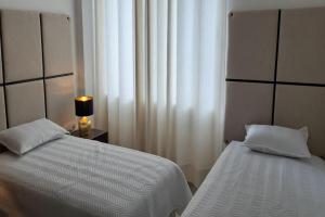 - une chambre avec deux lits et une lampe à côté d'une fenêtre dans l'établissement Elegante apartamento en Condominio Baruc II, à Santa Cruz de la Sierra