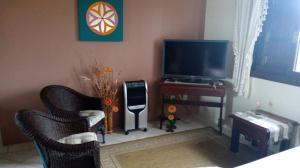 a living room with a television and a table and chairs at Apartamentos Di Armazzem in Torres