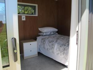 un piccolo letto in una piccola stanza con finestra di Waihi Gold Alpacas 3 or 4 people a Waihi
