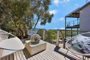 eine Holzterrasse mit Stühlen, einem Tisch und einer Vase in der Unterkunft Beachside House in Tootgarook