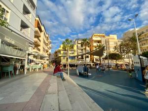 a man sitting on a sidewalk in a city at Bedroom Medanomar 2 in El Médano