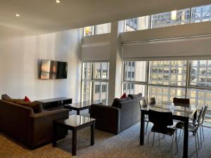 a living room with couches and tables and a large window at Quest on William in Melbourne