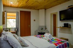 Un dormitorio con una cama con un televisor en la pared. en Pousada Polessas, en Visconde De Maua