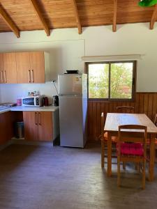 a kitchen with a table and a refrigerator at Cabañas Huenehue in Panguipulli