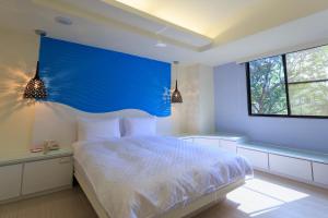a bedroom with a large bed with a blue headboard at Travelyoung Hotel in Kaohsiung