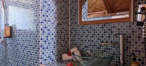 bagno piastrellato blu con vasca e specchio di Pension Les Trois Cascades a aUturoa