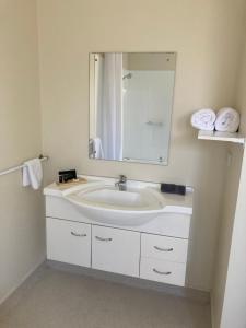 a bathroom with a sink with a mirror and towels at Heritage Highway Motel in Hokitika