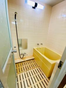 uma casa de banho com uma banheira amarela e um espelho. em KR Apartment in Kanazawa em Kanazawa
