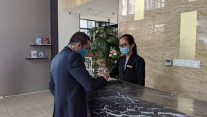 two people wearing face masks standing at a counter at Liberty Hotel Thamrin Jakarta in Jakarta