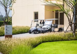 un carro de golf estacionado frente a un edificio en Eastin Thana City Golf Resort Bangkok en Samutprakarn