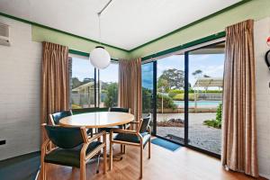 a dining room with a table and chairs and a large window at Emmanuel Holiday Apartment in Lakes Entrance