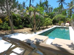 a swimming pool with two lounge chairs next to a villa at Breathe Villa Meno in Gili Meno