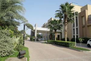 ein Gebäude mit Palmen neben einer Straße in der Unterkunft Tivoli Grand Resort in Neu-Delhi