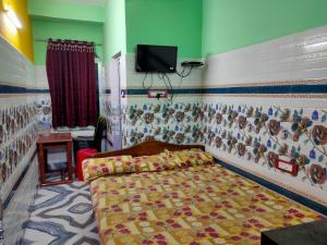a bedroom with a bed and a tv on the wall at Milan Guest House in Digha