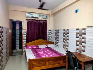 a bedroom with a bed and a table and a window at Milan Guest House in Digha