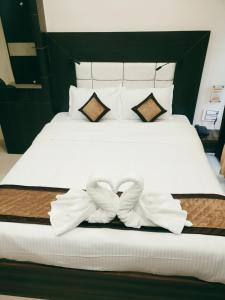 a bed with white sheets and pillows with bows at Citi Inn in Patna