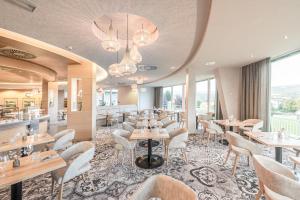 a restaurant with tables and chairs and windows at Hotel und Therme NOVA in Köflach