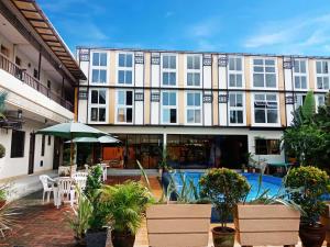 a building with a swimming pool and a patio with plants at Aerostop Hotel and Restaurant in Plaridel