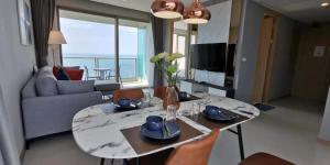 a living room with a table and chairs with a view of the ocean at Riviera Jomtien by Daisy Pattaya in Jomtien Beach