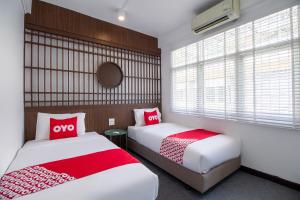 1 dormitorio con 2 camas y almohadas rojas y blancas en OYO 994 Kudi Hostel en Bangkok