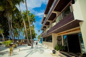 a building on the beach with palm trees in front of it at Kaani Beach Hotel in Maafushi