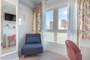 Habitación con silla azul y ventana en Cruces Metro Rooms en Barakaldo