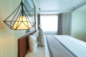ein Schlafzimmer mit einem Bett mit einer Lampe und einem Fenster in der Unterkunft Holiday One Can Tho Hotel in Cần Thơ