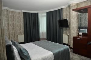 une chambre d'hôtel avec un lit et une télévision dans l'établissement SARDUR HOTEL, à Bostaniçi