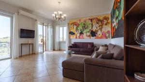 a living room with a couch and a tv at San Martino Holiday Apartments in Capo dʼOrlando