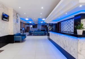 a lobby with a bar with blue lighting at ROOMS by Alexandra Hotel in St. Julianʼs