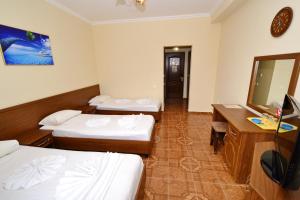 a room with two beds and a desk and a mirror at Hotel Elefteriya in Vityazevo